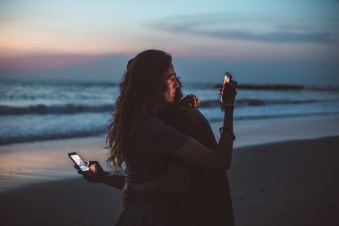 couple hugging and using smartphone near sea on sunset 4555321